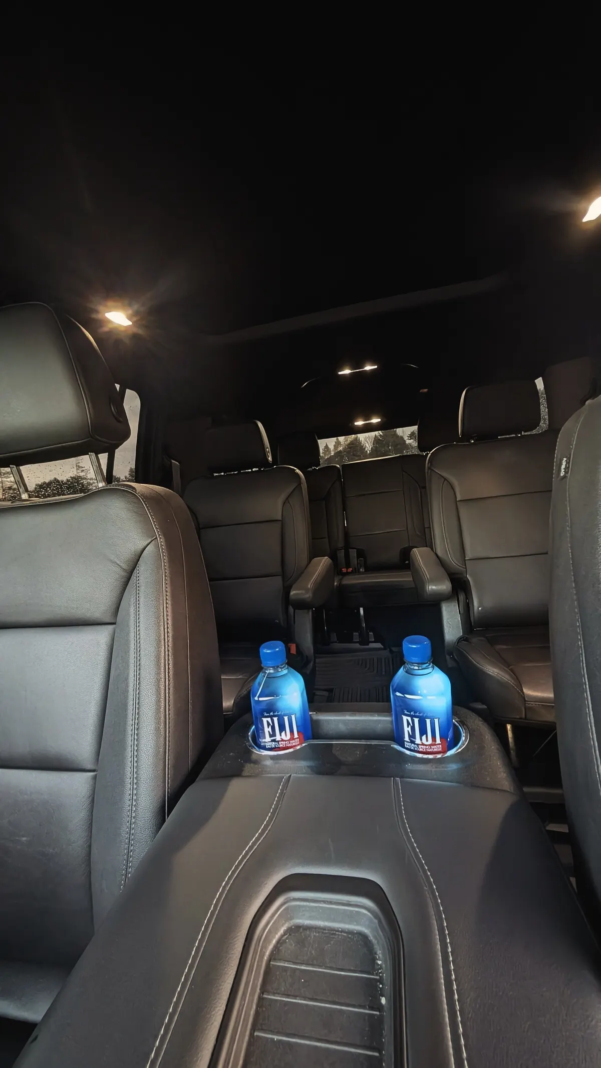 Inside the Polaris Reserve Suburban — leather captain's chairs with chilled water ready for guests